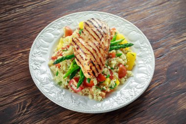 kuskus salata ızgara tavuk ve kuşkonmaz beyaz tabakta. ahşap rustik masa. sağlıklı gıda