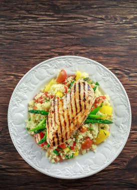 kuskus salata ızgara tavuk ve kuşkonmaz beyaz tabakta. ahşap rustik masa. sağlıklı gıda