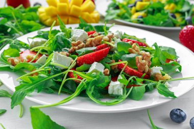 Taze çilek, mango, beyaz peynir ile blueberrie salatası, beyaz tabakta roka
