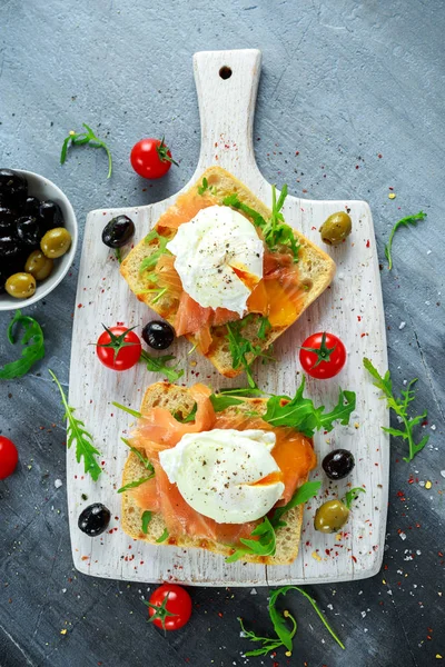 Somon füme, rucola, zeytin ve beyaz tahta üzerinde sebze ızgara ekmek üzerine haşlanmış yumurta. sağlıklı kahvaltı