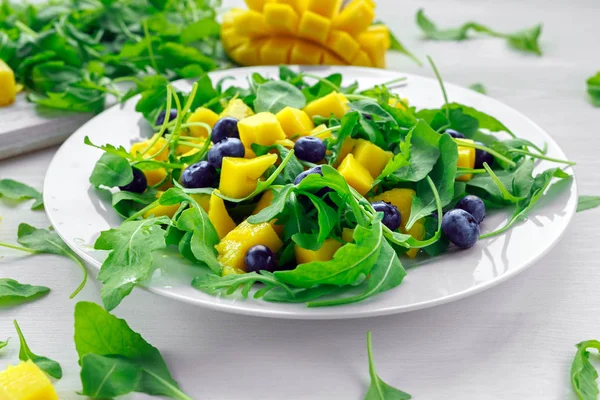 Mango, blåbär sallad med ruccola på vit platta — Stockfoto