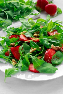 Beyaz tabakta roka ile taze çilek salatası