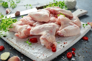 Taze çiğ tavuk kanatları kekik, kırmızı biber, tuz, biber, sarımsak ile beyaz kesme tahtası