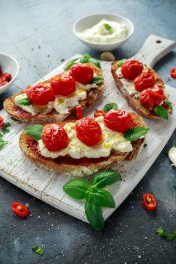 Domates Ricotta Bruschetta güneş ile kurutulmuş domates Yapıştır, zeytinyağı kahverengi ekmek ve fesleğen