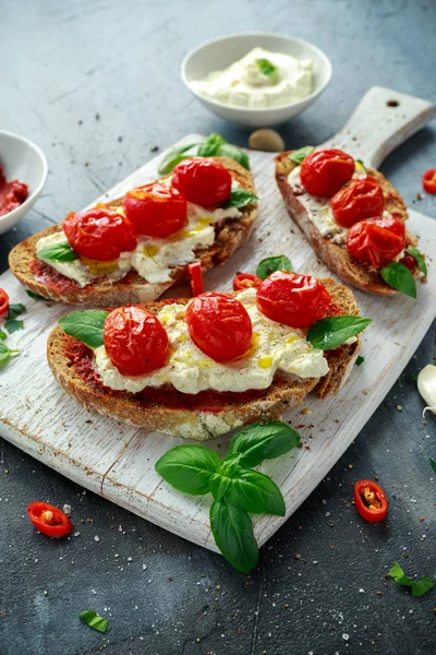Domates Ricotta Bruschetta güneş ile kurutulmuş domates Yapıştır, zeytinyağı kahverengi ekmek ve fesleğen