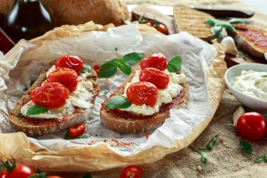Domates Ricotta Bruschetta güneş ile kurutulmuş domates Yapıştır, zeytinyağı kahverengi ekmek ve fesleğen