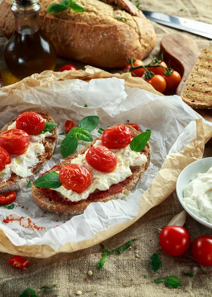 Tomat Ricotta Bruschetta med solen torkade tomater pasta, olivolja brunt bröd och basilika — Stockfoto