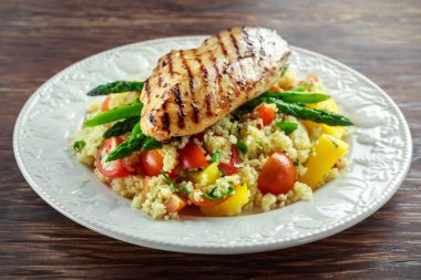 kuskus salata ızgara tavuk ve kuşkonmaz beyaz tabakta. ahşap rustik masa. sağlıklı gıda