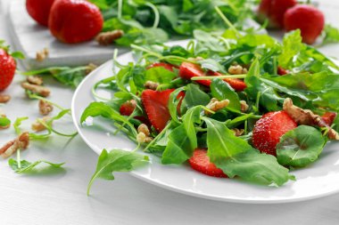 Beyaz tabakta roka ile taze çilek salatası