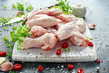 Taze çiğ tavuk kanatları kekik, kırmızı biber, tuz, biber, sarımsak ile beyaz kesme tahtası