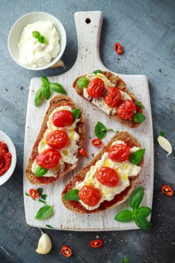 Domates Ricotta Bruschetta güneş ile kurutulmuş domates Yapıştır, zeytinyağı kahverengi ekmek ve Beyaz ahşap tahta fesleğen.