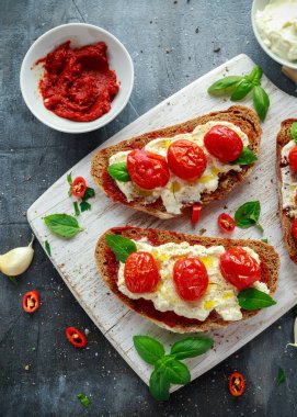 Domates Ricotta Bruschetta güneş ile kurutulmuş domates Yapıştır, zeytinyağı kahverengi ekmek ve Beyaz ahşap tahta fesleğen.