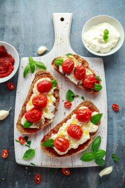 Domates Ricotta Bruschetta güneş ile kurutulmuş domates Yapıştır, zeytinyağı kahverengi ekmek ve Beyaz ahşap tahta fesleğen.