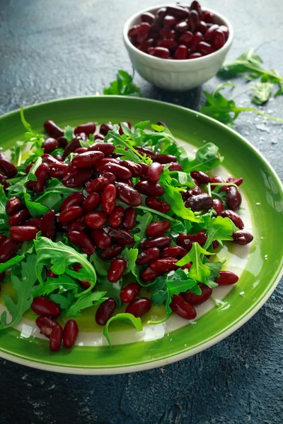 Красные бобы и дикие ракеты здоровый салат в зеленой тарелке — стоковое фото