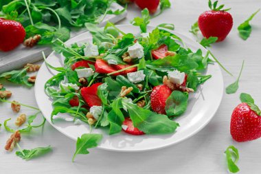 Beyaz tabakta roka ile taze çilek salatası