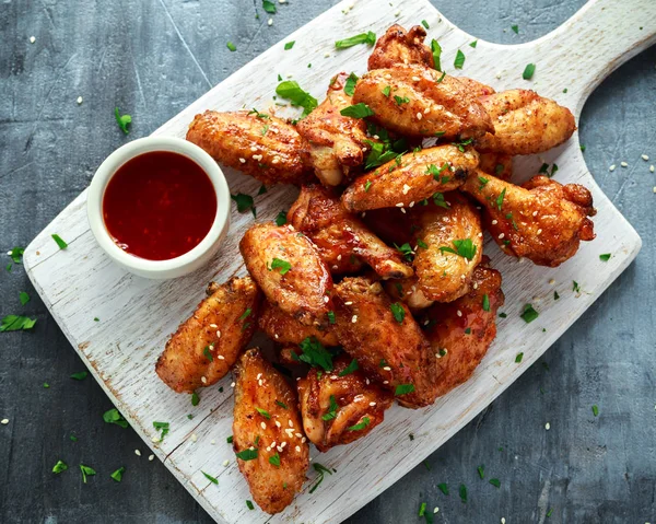 Ailes de poulet cuites au four aux graines de sésame et sauce chili sucrée sur planche de bois blanche . — Photo