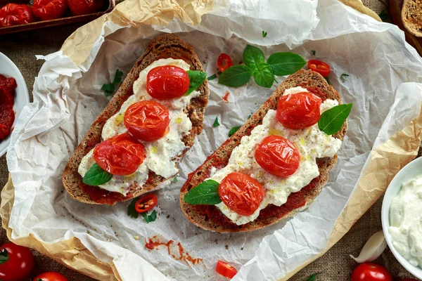 Tomat Ricotta Bruschetta med solen torkade tomater pasta, olivolja brunt bröd och basilika — Stockfoto