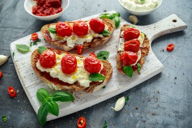 Domates Ricotta Bruschetta güneş ile kurutulmuş domates Yapıştır, zeytinyağı kahverengi ekmek ve Beyaz ahşap tahta fesleğen.