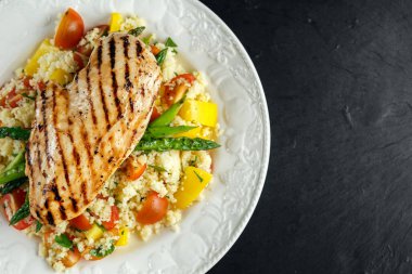 kuskus salata ızgara tavuk ve kuşkonmaz beyaz tabakta. Taş Masa. sağlıklı gıda