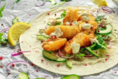 Taze balık Tortilla salatalık, kırmızı soğan, Kapari, limon, salata yaprakları ve çiğ sos ile. Sağlıklı gıda