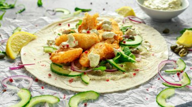 Taze balık Tortilla salatalık, kırmızı soğan, Kapari, limon, salata yaprakları ve çiğ sos ile. Sağlıklı gıda