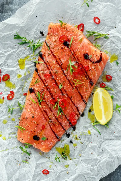 Filé de salmão temperado sobre papel de cozinha com sal marinho, pimenta, vinagre balsâmico, pimentas e alecrim. Pronto para cozinhar — Fotografia de Stock