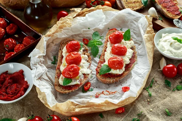 Domates Ricotta Bruschetta güneş ile kurutulmuş domates Yapıştır, zeytinyağı kahverengi ekmek ve fesleğen