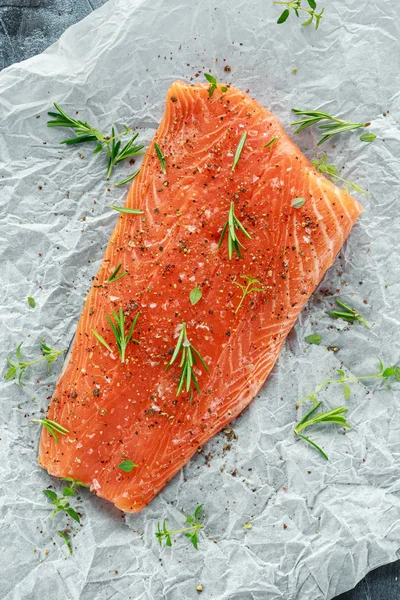 Приправлене філе лосося на кулінарному папері з морською сіллю, перцем та розмарином. Готовий готувати — стокове фото