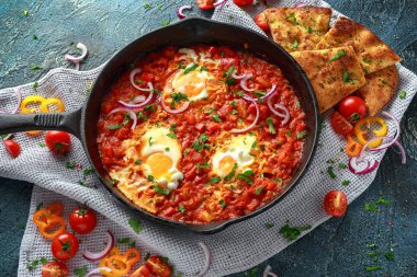 Lezzetli Breakfast Shakshuka demir Pan içinde Kızarmış yumurta domates, kırmızı, sarı biber, soğan, maydanoz, pide ve otlar. Sağlıklı gıda