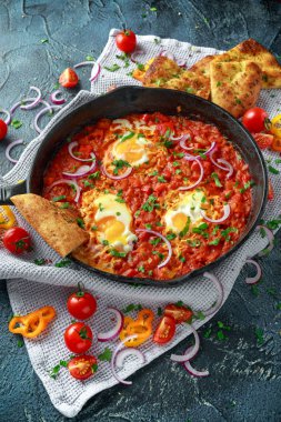 Lezzetli Breakfast Shakshuka demir Pan içinde Kızarmış yumurta domates, kırmızı, sarı biber, soğan, maydanoz, pide ve otlar. Sağlıklı gıda