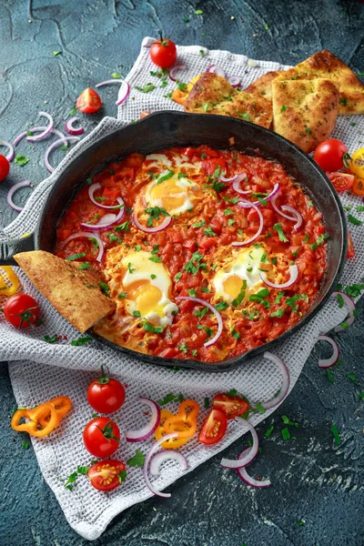 Lezzetli Breakfast Shakshuka demir Pan içinde Kızarmış yumurta domates, kırmızı, sarı biber, soğan, maydanoz, pide ve otlar. Sağlıklı gıda