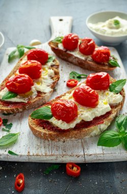 Domates Ricotta Bruschetta güneş ile kurutulmuş domates Yapıştır, zeytinyağı kahverengi ekmek ve Beyaz ahşap tahta fesleğen.