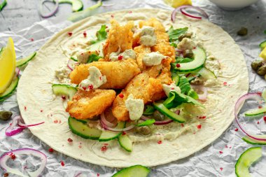Taze balık Tortilla salatalık, kırmızı soğan, Kapari, limon, salata yaprakları ve çiğ sos ile. Sağlıklı gıda