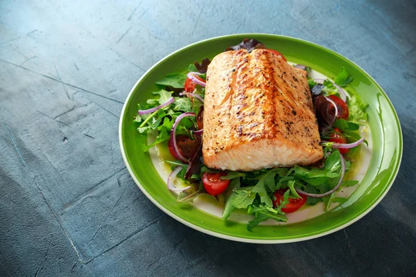 Baked salmon steak with tomato, onion, mix of green leaves salad in a plate. healthy food — Stock Photo, Image