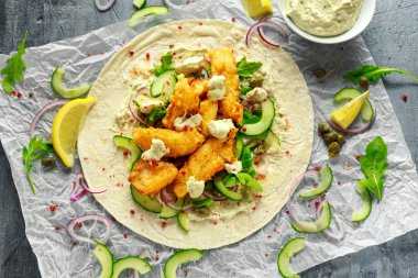 Taze balık Tortilla salatalık, kırmızı soğan, Kapari, limon, salata yaprakları ve çiğ sos ile. Sağlıklı gıda