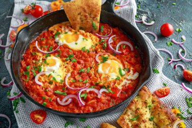 Lezzetli Breakfast Shakshuka demir Pan içinde Kızarmış yumurta domates, kırmızı, sarı biber, soğan, maydanoz, pide ve otlar. Sağlıklı gıda