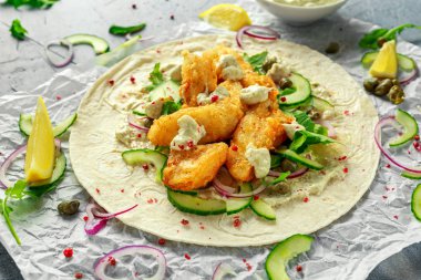 Taze balık Tortilla salatalık, kırmızı soğan, Kapari, limon, salata yaprakları ve çiğ sos ile. Sağlıklı gıda