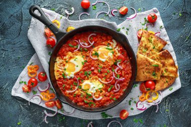 Lezzetli Breakfast Shakshuka demir Pan içinde Kızarmış yumurta domates, kırmızı, sarı biber, soğan, maydanoz, pide ve otlar. Sağlıklı gıda