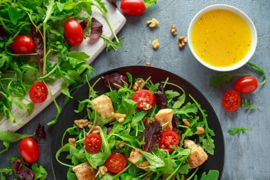 Taze salata tavuk göğsü, roka, fındık ve ahşap bir masa içinde siyah plaka üzerinde domates ile.