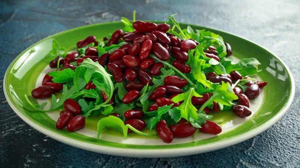 Haricots rouges et salade santé roquette sauvage dans une assiette verte — Photo