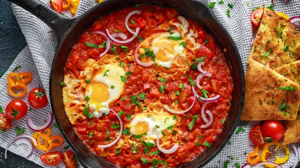 Lezzetli Breakfast Shakshuka demir Pan içinde Kızarmış yumurta domates, kırmızı, sarı biber, soğan, maydanoz, pide ve otlar. Sağlıklı gıda
