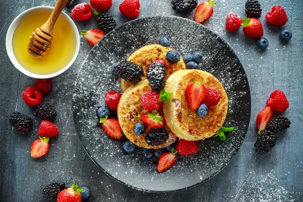 Britânico Crumpets café da manhã com mirtilos, morangos, amoras, framboesas regadas com açúcar de confeiteiro — Fotografia de Stock