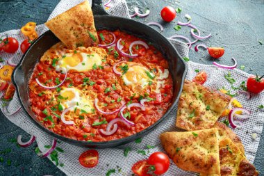 Lezzetli Breakfast Shakshuka demir Pan içinde Kızarmış yumurta domates, kırmızı, sarı biber, soğan, maydanoz, pide ve otlar. Sağlıklı gıda