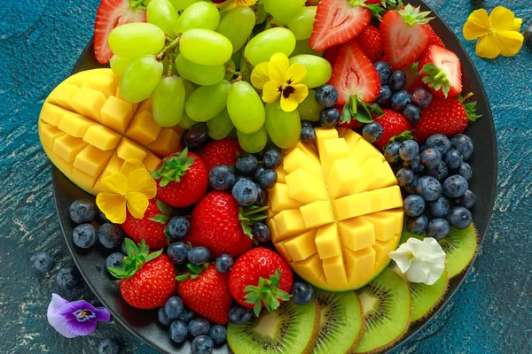 Mango, çilek, yaban mersini, kivi ve Yeşil üzüm ile renkli karışık meyve tabağı. Sağlıklı gıda