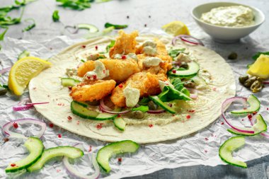 Taze balık Tortilla salatalık, kırmızı soğan, Kapari, limon, salata yaprakları ve çiğ sos ile. Sağlıklı gıda