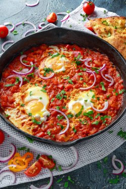 Lezzetli Breakfast Shakshuka demir Pan içinde Kızarmış yumurta domates, kırmızı, sarı biber, soğan, maydanoz, pide ve otlar. Sağlıklı gıda
