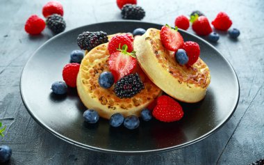 İngiliz Crumpets kahvaltı yaban mersini, çilek, böğürtlen, ahududu ile drizzled ile krema şeker