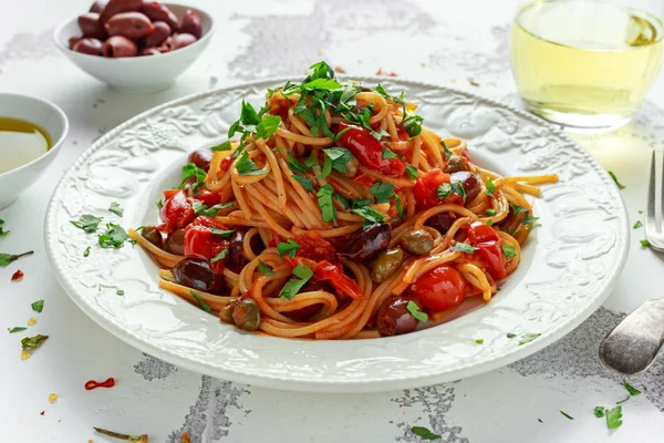 Macarrão italiano vegetariano Alla Puttanesca com alho, azeitonas, alcaparras com na placa branca . — Fotografia de Stock