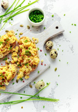 Ev yapımı bıldırcın karıştırılmış yumurta çıtır çıtır kızarmış ekmek, yeşil soğan ile ekmek, beyaz tahta üzerinde chives.