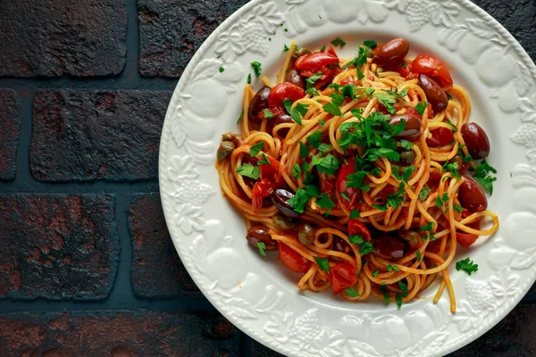 Pasta italiana vegetariana Allá Puttanesca con ajo, aceitunas, alcaparras con sobre plato blanco . —  Fotos de Stock